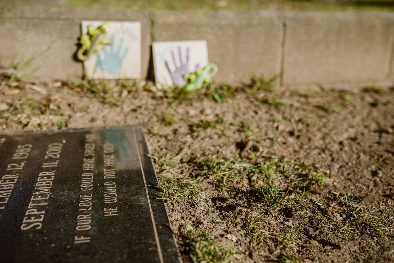 Close-up of a gravestone with handprint tiles, symbolizing remembrance in a memorial park.