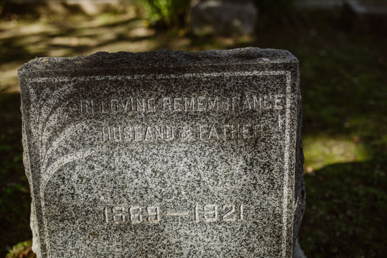 About Close-up of a granite tombstone engraved with 'In Loving Remembrance' and dates from 1869-1921.